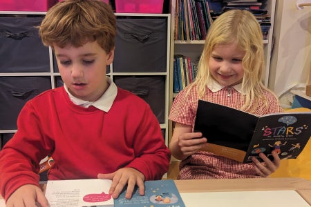 Two children reading books at their school desks.