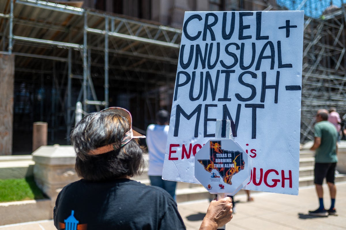 Protester holding sign that reads: CRUEL+UNUSUAL PUNISHMEMT