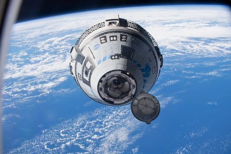 Boeing’s Starliner approaching the International Space Station as it flies 268 miles above the South Pacific, which is seen in the background.