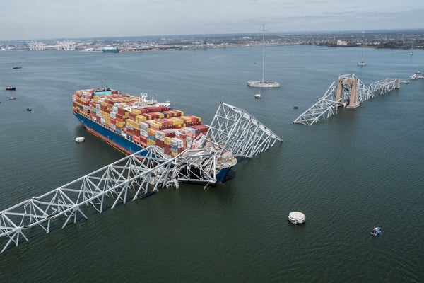 Container ship loaded with red and yellow boxes crashes into a steel bridge.