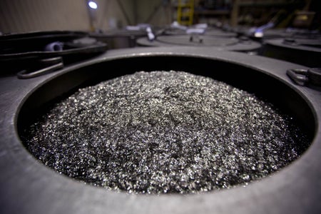 Small pieces of silvery metal visible piled in a cavity in the floor of a factory