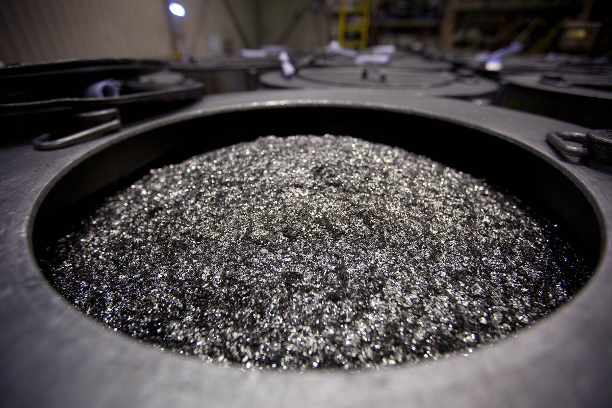Small pieces of silvery metal visible piled in a cavity in the floor of a factory