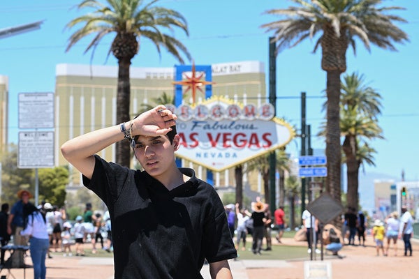 A person reacts to the heat wave in front of the Las Vegas sign