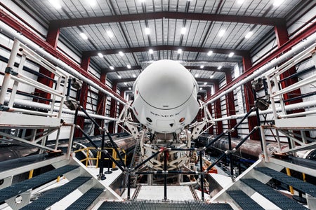 Spaceship SpaceX Crew Dragon, atop the Falcon 9 rocket, inside the hangar.