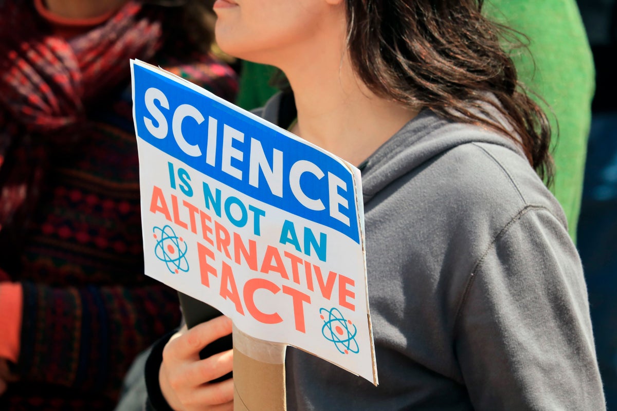 Unidentified woman holds a protest sign saying 