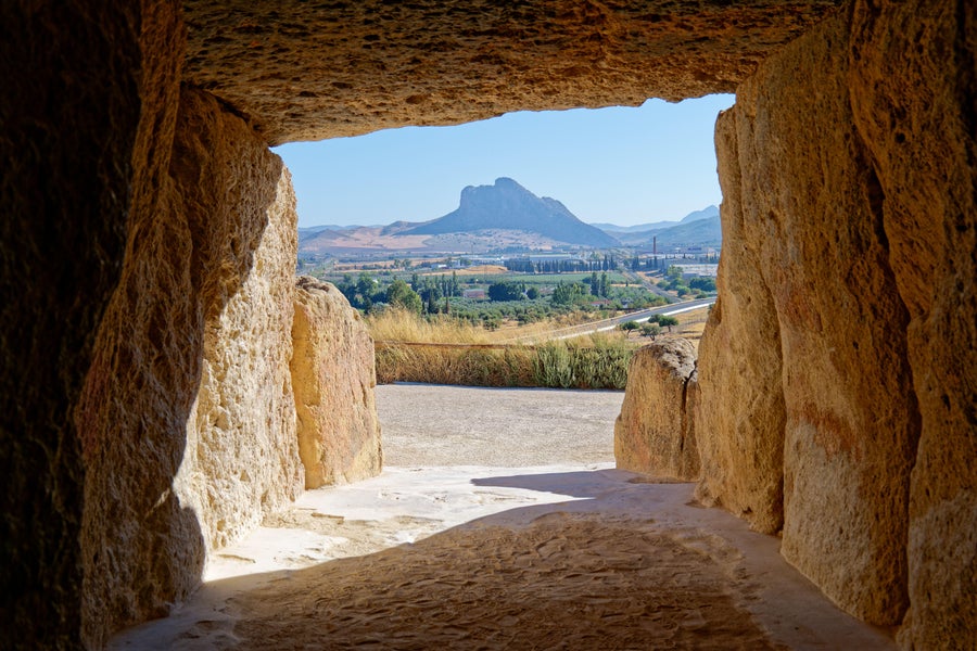 Interior of the megalithic monument Dolmen of Menga looking at Antequera with the natural monument The Lovers' Rock in the background.