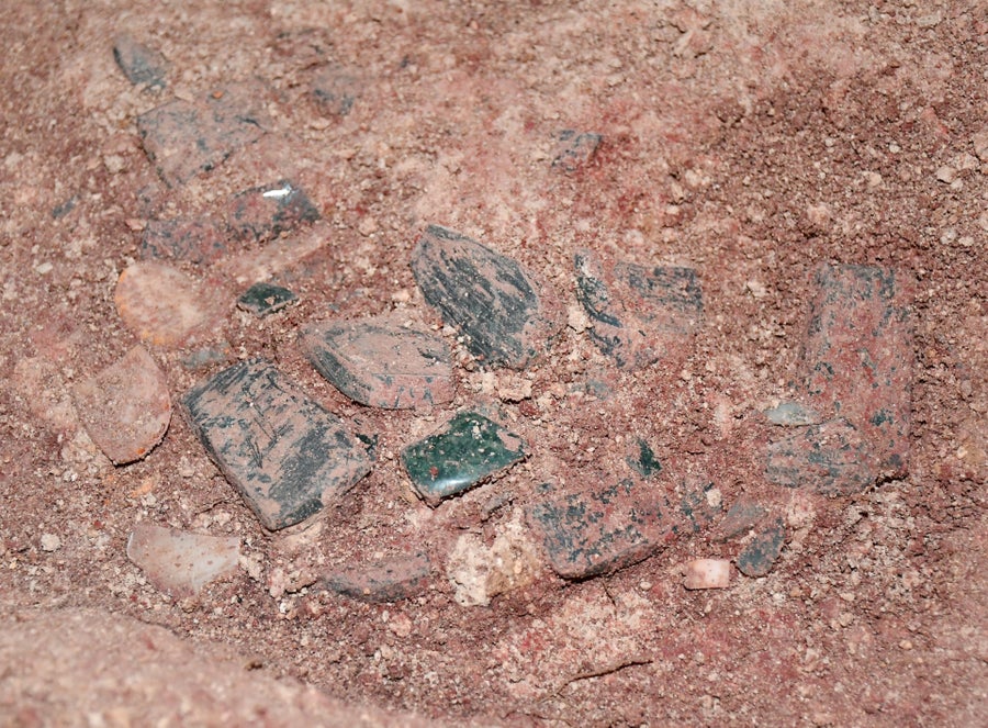 Peças de jadeita espalhadas no piso de terra vermelha