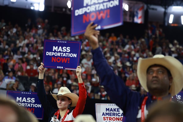 Some attendees of the Republican National Convention hold "Mass Deportation Now" signs on July 17, 2024 in Milwaukee, Wisconsin.