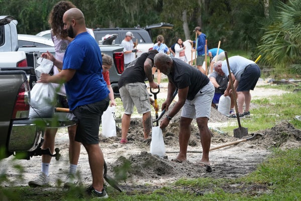 Pinellas County residents can be seen next to vehicles filling sandbags with shovels at John Chestnut Park in Palm Harbor, Florida on October 6, 2024