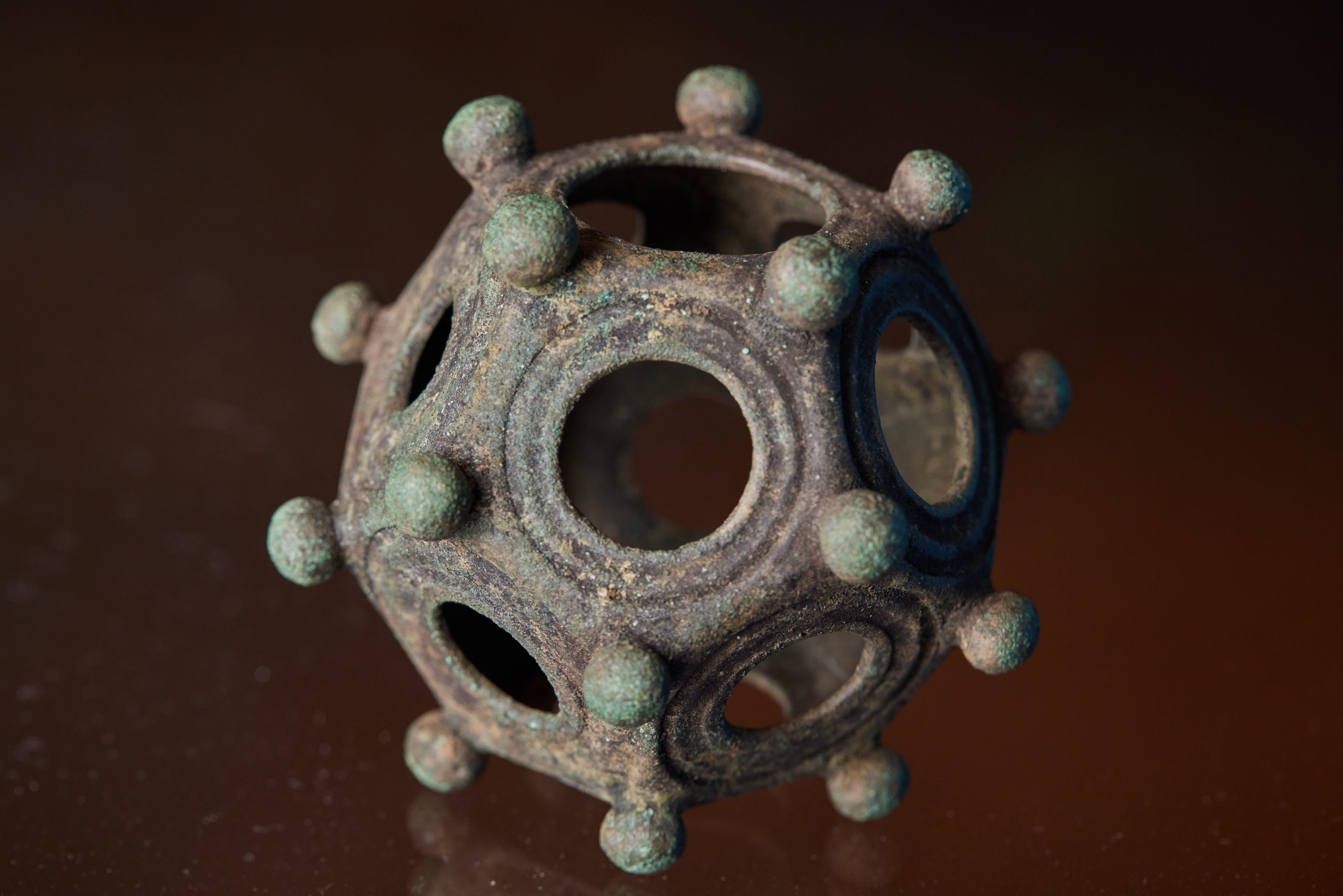 Metal dodecahedra featuring a number of round holes, with knobs framing the holes - a 12-sided, hollow object with knobs.