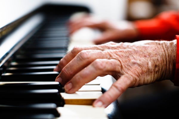 Vieilles mains ridées aux poignets rouges jouant du piano.