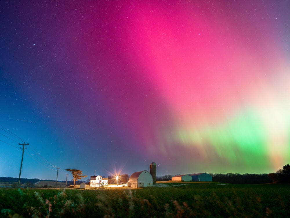 Una espectacular franja de color rosa brillante, con algo de verde neón, aparece en el cielo sobre un edificio.