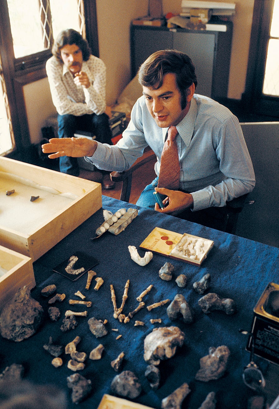 A man sitting down with an array of small fossils on the table in front of him