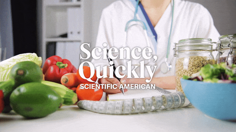 A person in a lab coat and a stethoscope writes in a notebook, with foods like bell peppers and lettuce in the foreground.
