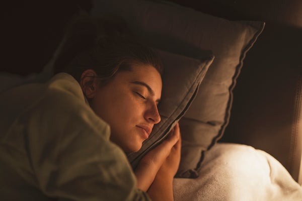 Lamp illuminating sleeping young woman at night