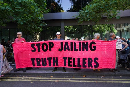 Supporters hold a banner that reads "Stop Jailing Truth Tellers".