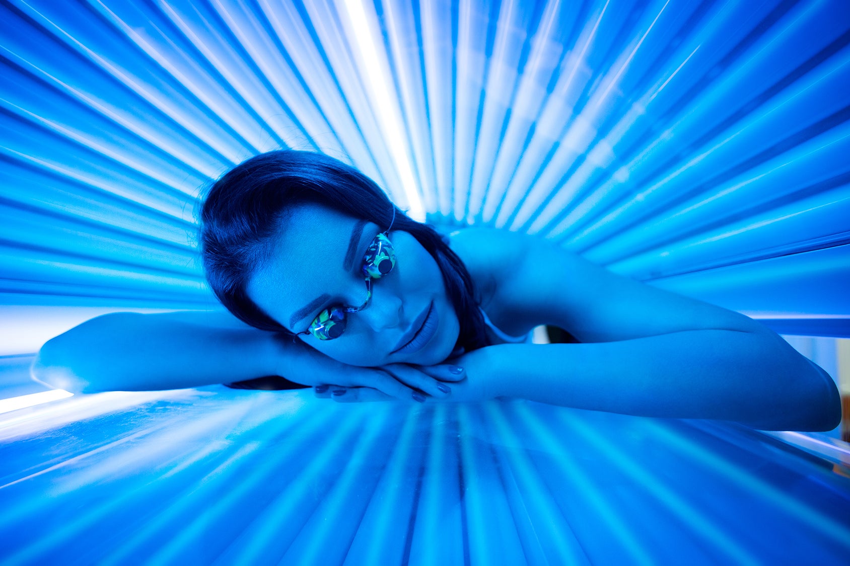 Woman under blue lights of tanning bed with goggles