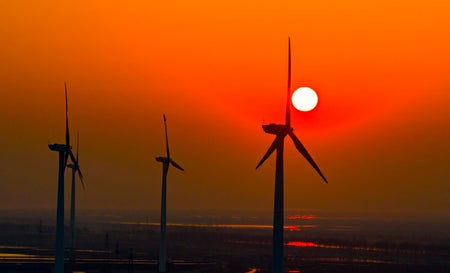 Wind turbines rotates against the wind in a vast coastal mudflat in China
