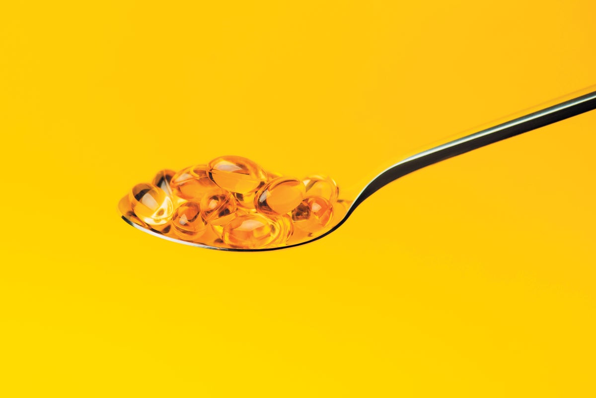Omega 3 Fish Oil capsules in a spoon against a yellow background