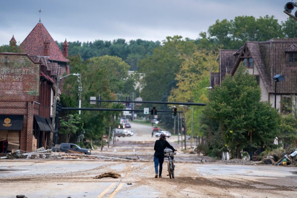 A person walks by bicycle and surveys a hurricane-damaged town.