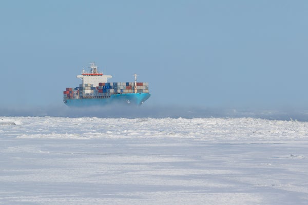 Cargo filled with boxy in red yellow and blue containers navigating through ice.