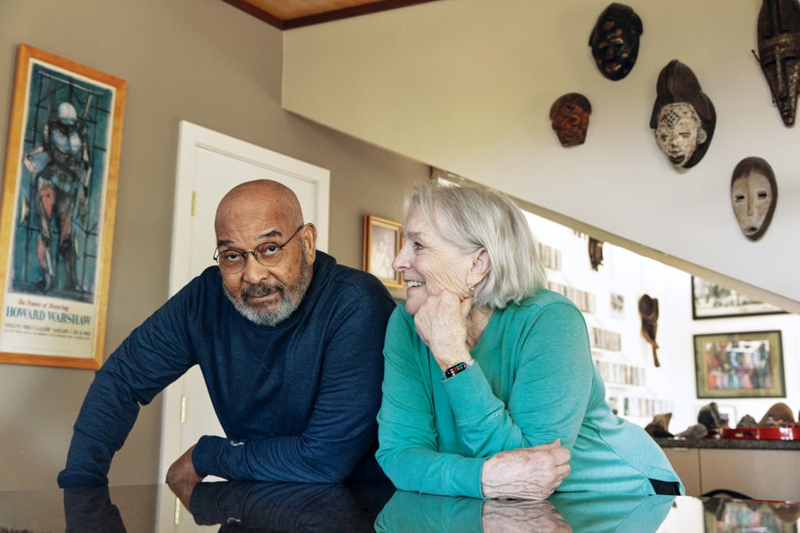 A man and woman leaning against a counter in a home.