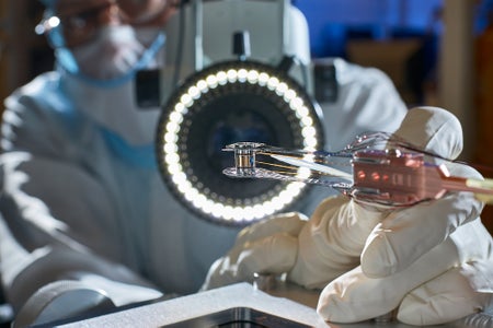 Close up of a Target Pre-Fabrication Facility Technician bonding Thermal Mechanical Packages (TMP), fill lines, and diagnostic band windows using adhesive placed on a human hair