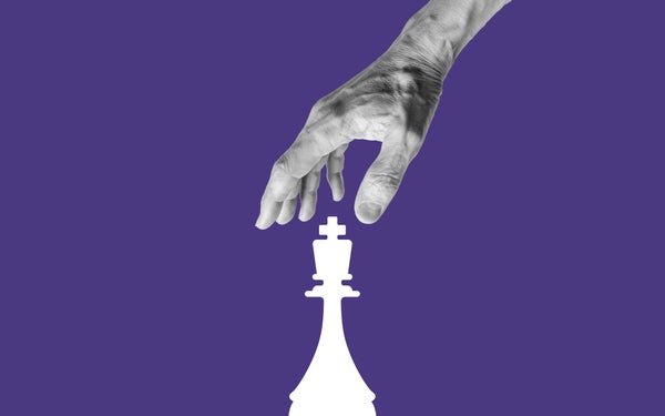 Human hand taking white King chess piece against purple background