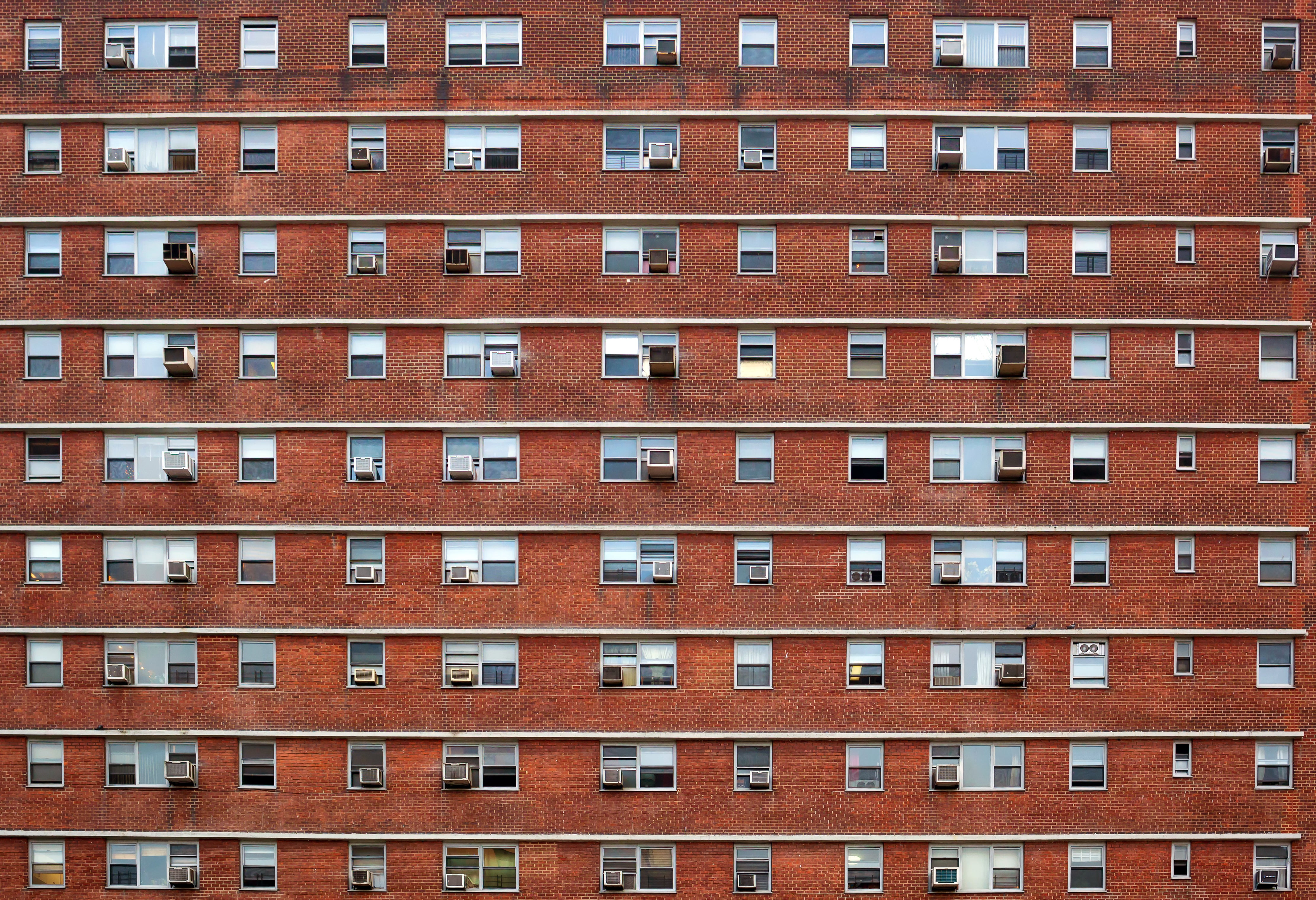 Brick guilding with identical small windows and Air conditioners.