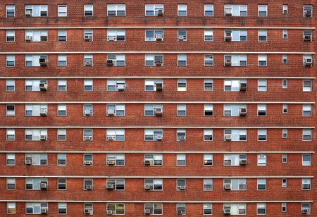 Brick guilding with identical small windows and Air conditioners.