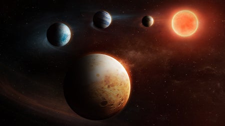 An illustration of four colorful planets in orbit around a red dwarf star.
