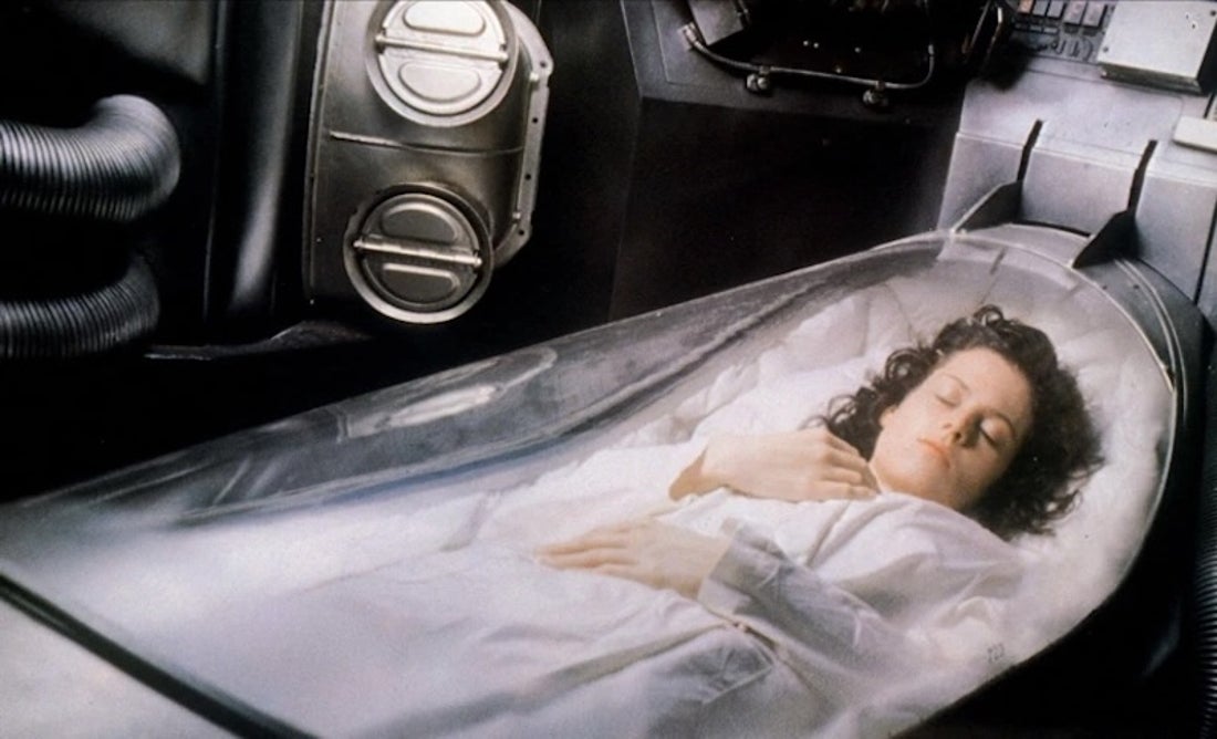Woman laying in cryo-sleep pod from movie Alien.