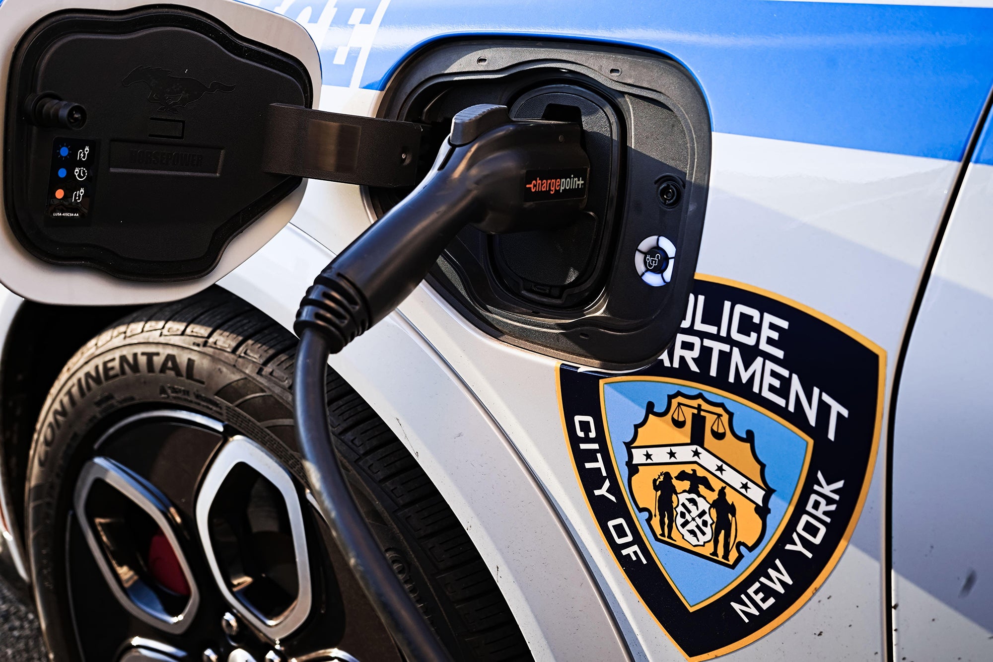 City of New York Police Department EV patrol car charging with ChargePoint electric vehicle plug on street outside