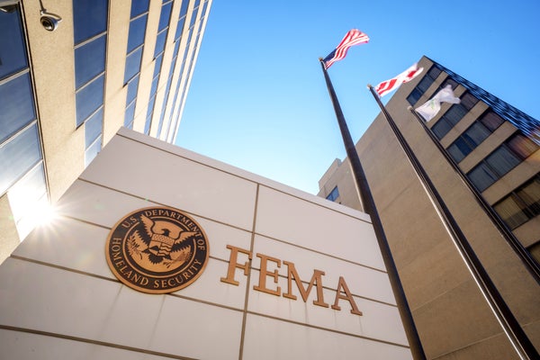 The sun flares behind the sign of the FEMA Building