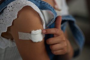 A photo of a child with bandage on their arm after receiving a vaccine.