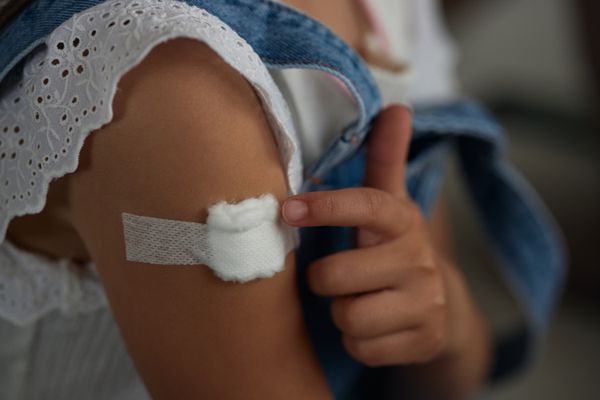 A photo of a child with bandage on their arm after receiving a vaccine.
