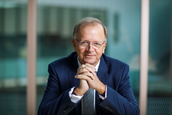 Portrait of a man in a suit looking directly at the camera with his hands clasped