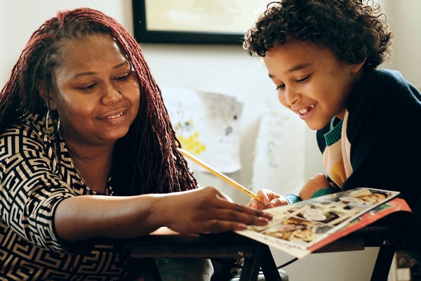 A mom and son looking at a book.