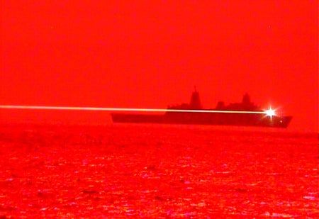 Monochromatic red image showing ship at sea with a laser shooting across frame