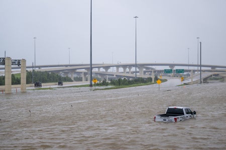 An abandoned white pick up truck in floodwater on a highway.