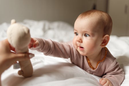 Baby girl playing with a toy while lying on the bed