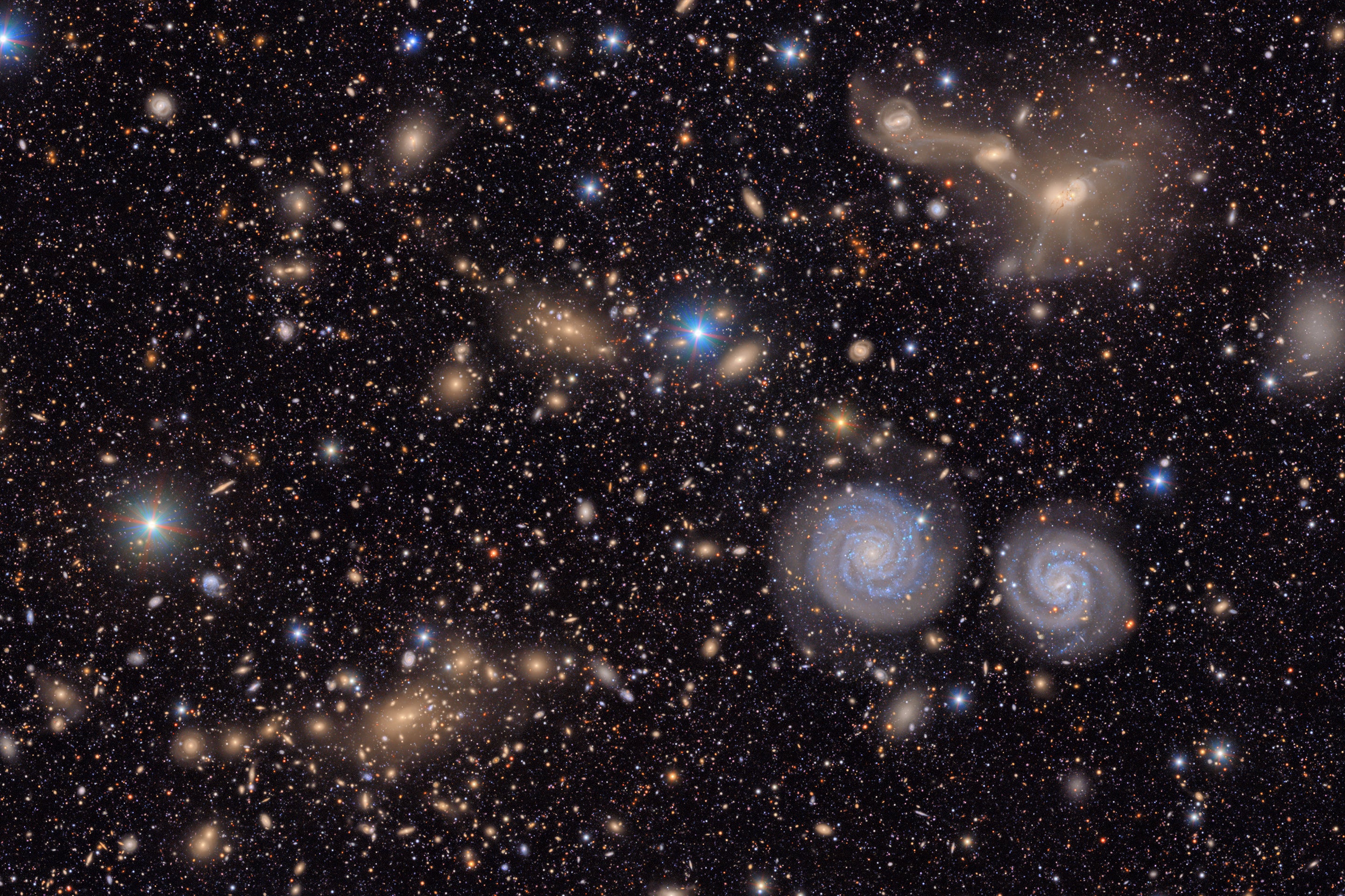 Many stars and galaxies including two spiral galaxies and three merging galaxies