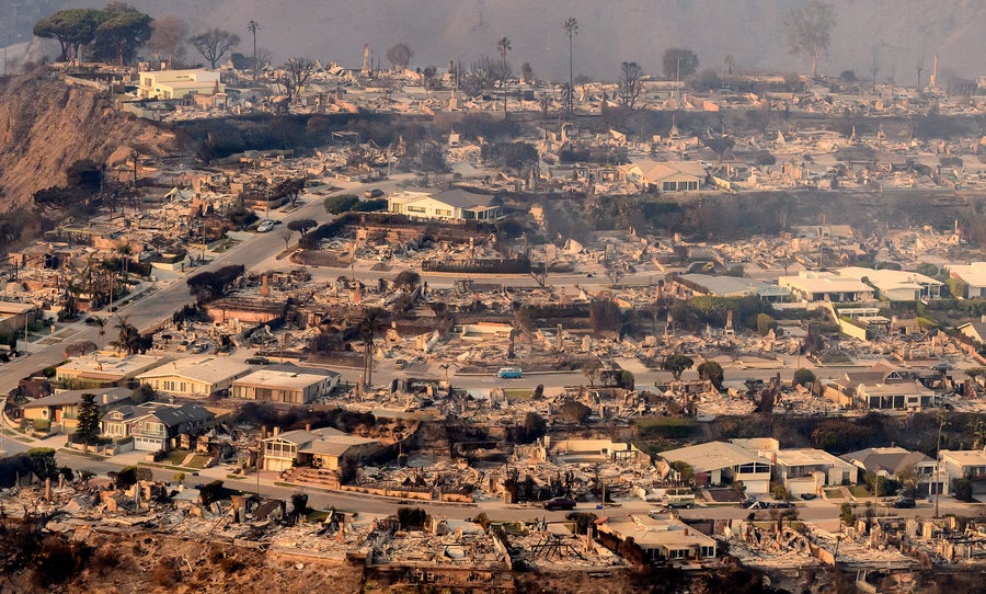 In this aerial view taken from a helicopter, an antique, blue and white VW bus sitting parked on the street in the center of burned homes are seen from above during the Palisades fire near the Pacific Palisades neighborhood of Los Angeles, California on January 9, 2025 as massive wildfires that engulfed whole neighborhoods and displaced thousands of residents remained totally uncontained. Swaths of the United States' second-largest city lay in ruins, with smoke blanketing the sky and an acrid smell pervading almost every building
