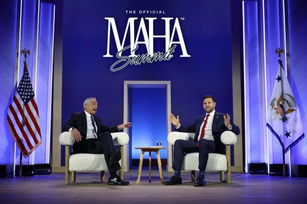 JD Vance and RFK, Jr. sit on stage in front of a MAHA sign during the MAHA summit in Washington, D.C.