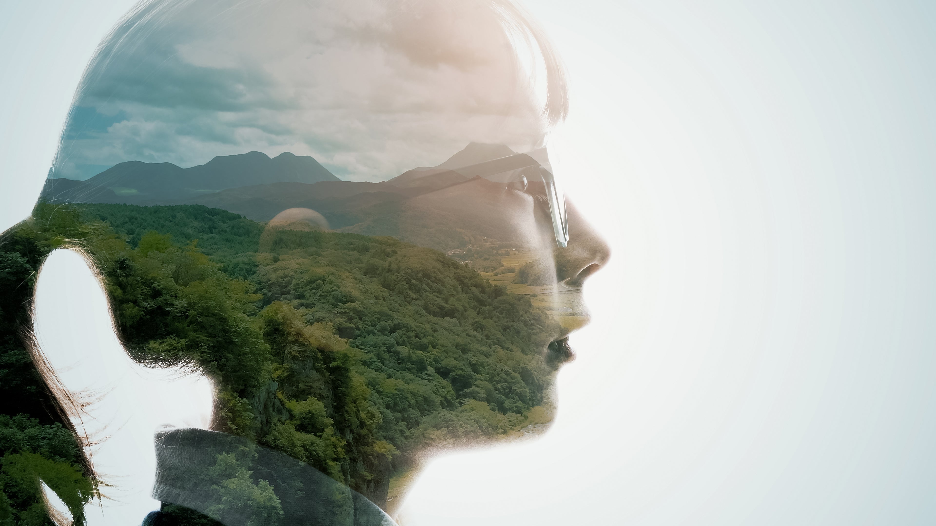 A double exposure image showing profile of a young girl and a landscape.