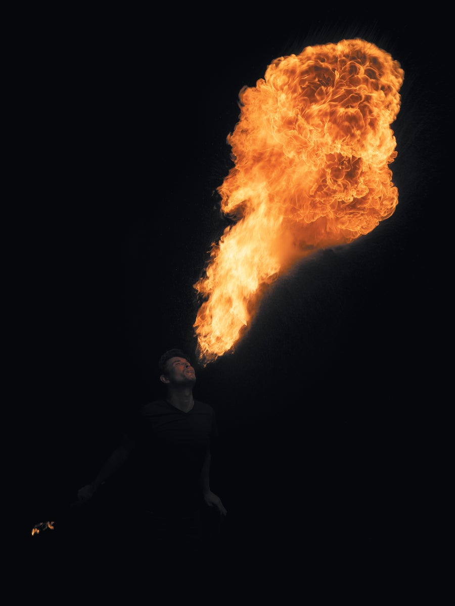 A person blowing fire from their mouth in the dark