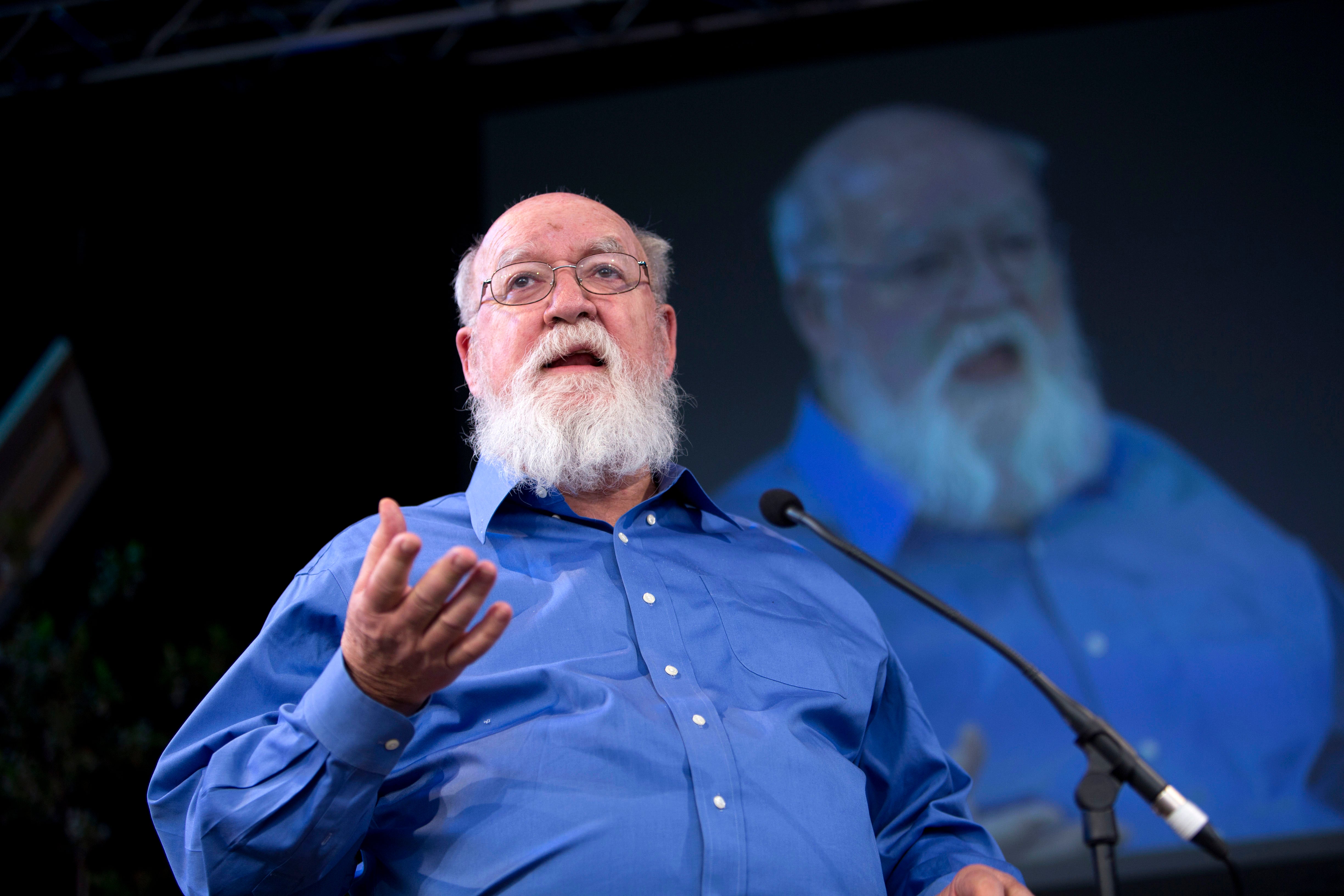 Daniel Dennett speaking as his image is displayed on screen in the background