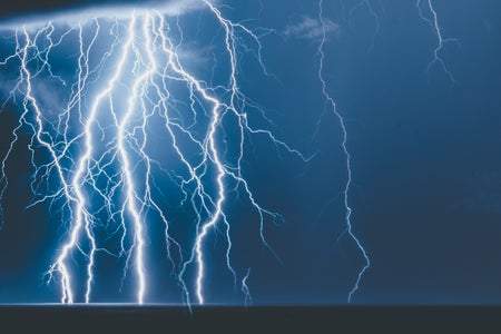 Lightning strikes against a dark blue sky