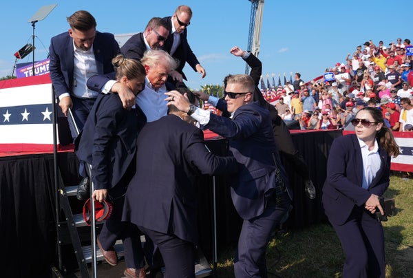 Secret service agents carry a wounded Donald Trump off stage