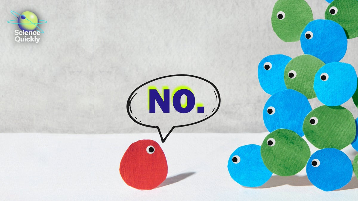 An illustration of personified dots each having one googly eye with most being blue and green clumped in a group to the right looking at the lone red dot with a 